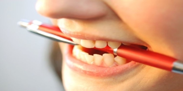 Close-up of a person holding a pen in their mouth AI-generated content may be incorrect.